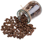 Glass jar tipped over with coffee beans spilling out onto a white surface.