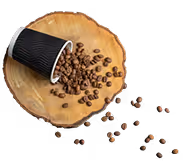 Black paper cup tipped over spilling coffee beans onto a wooden round board with some beans scattered beyond it.